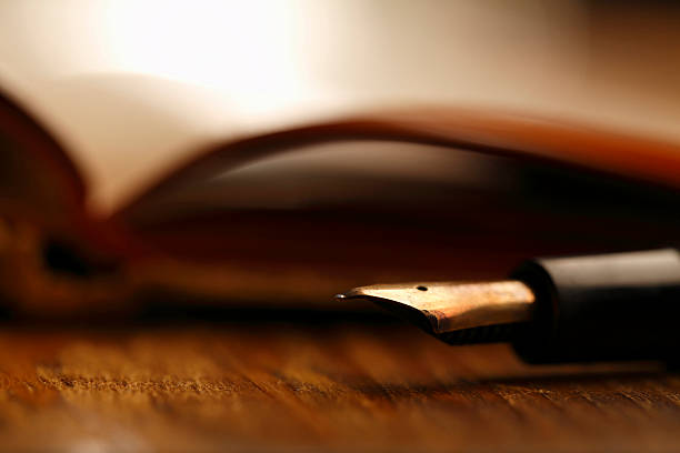 Antique fountain pen on old notepad - book, wooden table. Close-up.The grain and texture added. Selective focus. Very shallow depth of field for soft background.