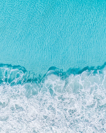 A vibrant backdrop featuring an aerial view of crashing ocean waves in shades of blue and white