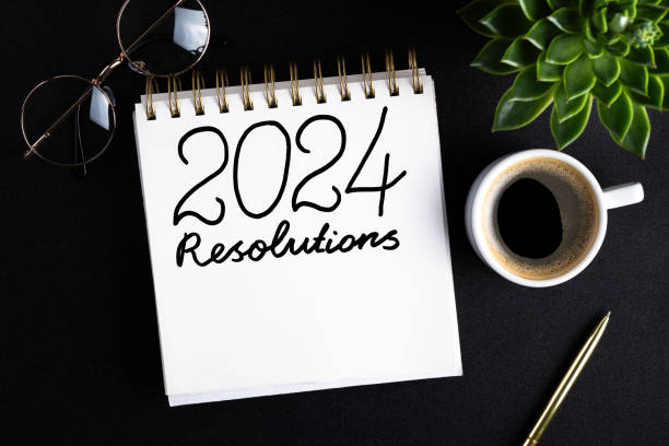 istock 2024 New year resolutions on desk. 2024 goals list with notebook, coffee cup, plant on black table. Resolutions, plan, goals, action, idea concept. New Year 2024 resolutions 1767607221