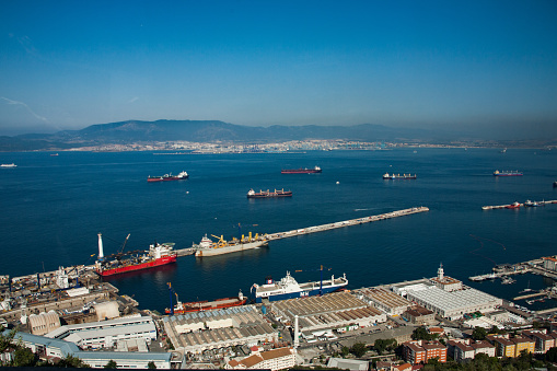 Gibraltar - June 21, 2017: View of Gibraltar Harbour with ships, docks and contaiers, a small industrial area. Town and port of Algeciras, Spain can be seen in the distance