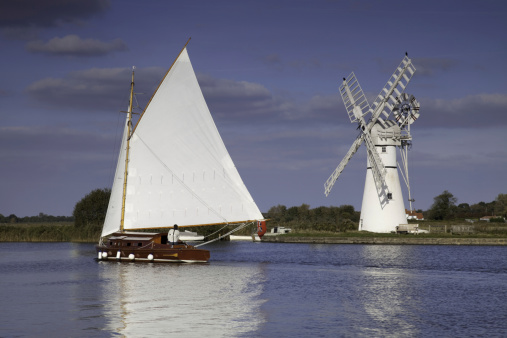 Traditional sailing wherry at Thurne Mill on the Norfolk Broads. Thurne Mill is owned by The Norfolk Windmills Trust and is a major landmark which can be seen for miles.  It marks the entrance to Thurne Dyke which leads down to the village of Thurne.