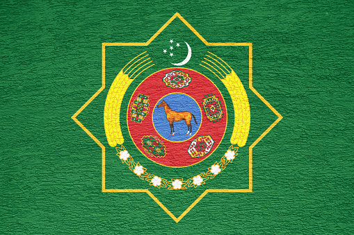 Flag and coat of arms of Turkmenistan on a textured background. Concept collage.