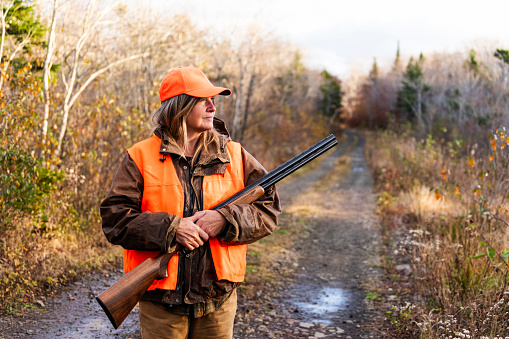 A female hunter with her chocolate Labrador retriever out hunting in the autumn for grouse.