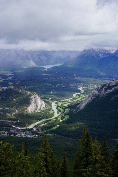 istock a valley surrounded by tall trees, with snow capped mountains in the background 1767657085
