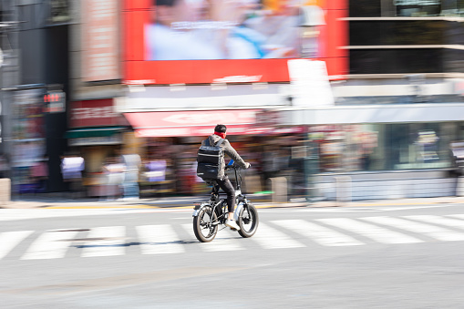 October 27th 2023, Shibuya, Tokyo Japan. Intentional slow shutter used to show movement and speed of a cyclist riding a bike delivering food in Tokyo.