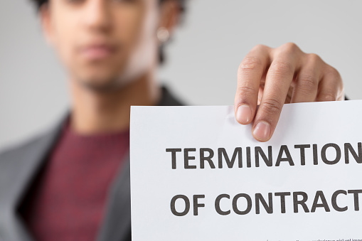 young unrecognizable man presents 'TERMINATION OF CONTRACT' noti
