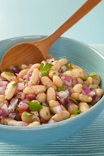 Italian cannelini bean salad of beans in lemon vinaigrette with red onion, rosemary, parsley and garlic.