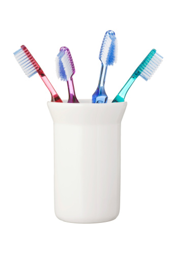 Four toothbrushes in holder against white background.