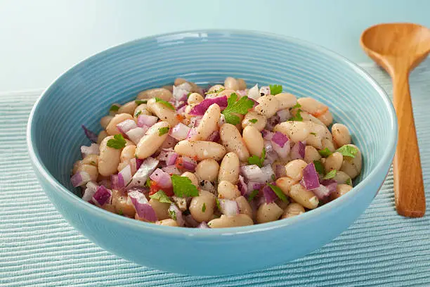 Italian cannelini bean salad of beans in lemon vinaigrette with red onion, rosemary, parsley and garlic.