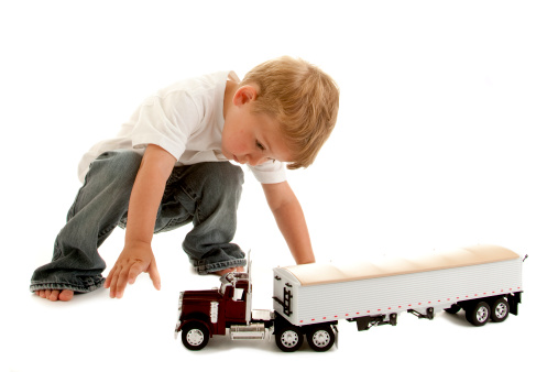 A little boy concentrates as he plays with his toy truck.