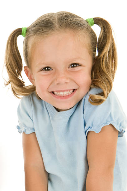 Adorable Young Girls Head Shot Beautiful smile and pigtails on the effervescent face of a 3 year old girl. She has her shoulders shrugged upward for this headshot. Pigtails stock pictures, royalty-free photos & images
