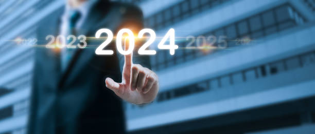 istock 2024. business man hand pointing on year 2024 with virtual screen on building background, goal target, change from 2023 to 2024, strategy, investment, business planning, happy new year concept 1767686921