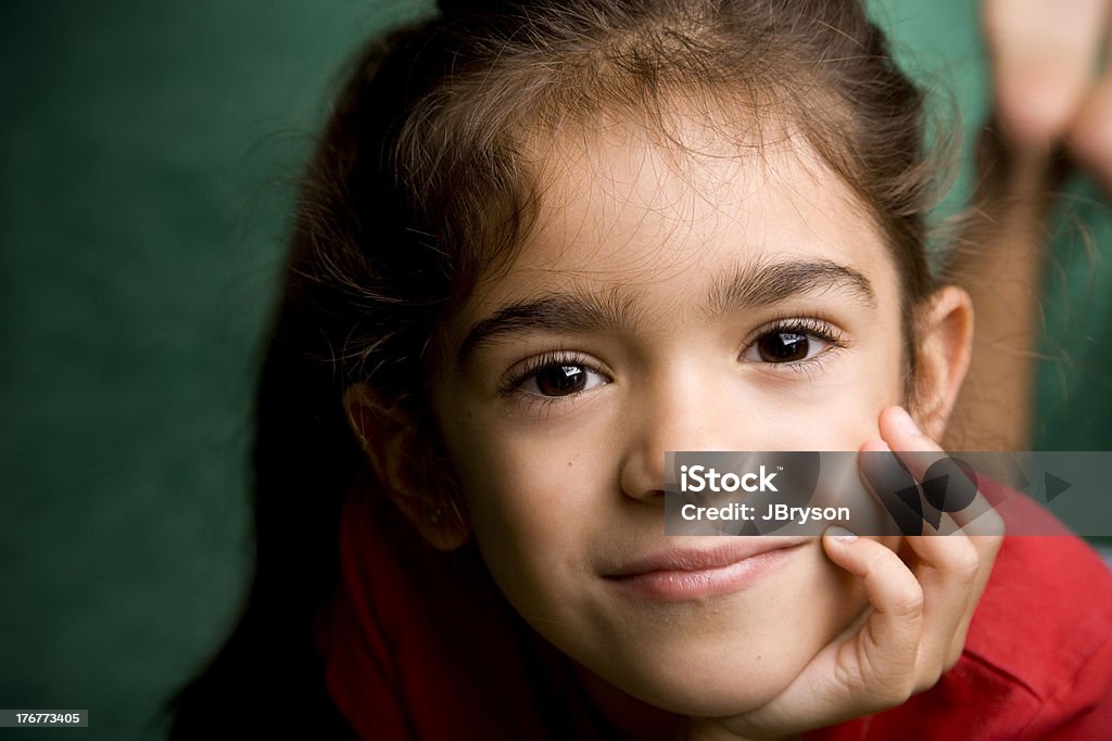 Hispanic bambina sorridente con in mano sul mento - Foto stock royalty-free di 4-5 anni