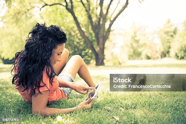 Donna Utilizzando La Tavoletta Digitale Al Parco - Fotografie stock e altre immagini di Abbigliamento casual - Abbigliamento casual, Adulto, Albero