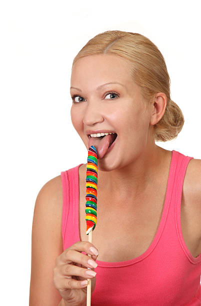 Young happy woman licking sweet lollipop stock photo