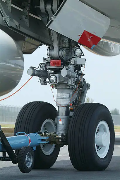 "Nose wheel (front landing gear) of very large, wide-body airplane being towed at an airport."