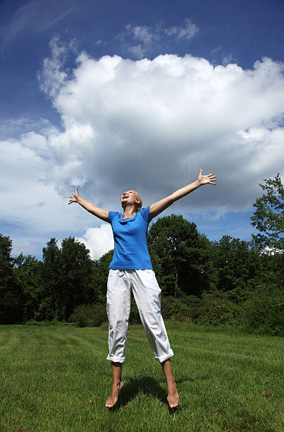 Happy young woman jumping in a field stock photo