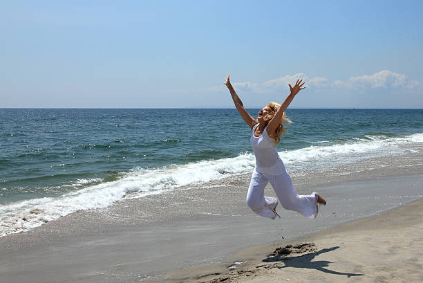 Happy woman jumping on a beach stock photo