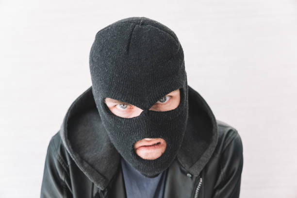 istock A thief in a black jacket. A man in black balaclava with an evil expression on his face. An aggressive bandit on a white background. The concept of crime or theft. 1767768461