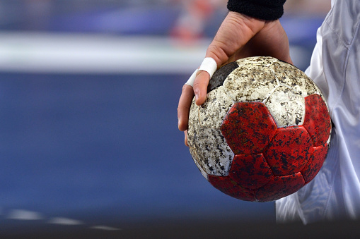 Handball Player with sportstape on his fingers, warming up while holding a handball