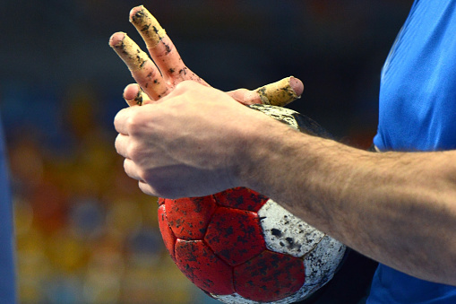 Handball Player with sportstape on his fingers, warming up while holding a handball