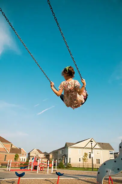 Photo of Little Girl Swings, Playground in the Suburbs