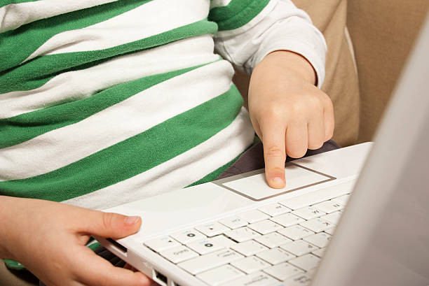 молодой ребенок применяет trackpad на белом компьютер нетбук - ipad 3 ipad white caucasian стоковые фото и изображения