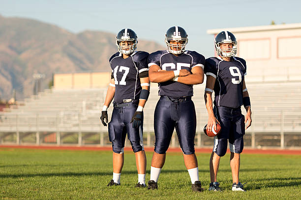 Football Players Three American football players pose for a portrait on the football field. american football field photos stock pictures, royalty-free photos & images