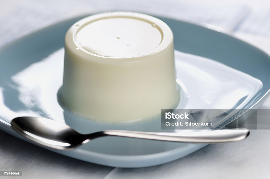 Panna cotta, S. Plain panna cotta on a blue plate with spoon Panna Cotta Stock Photo