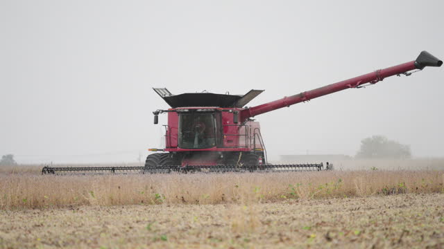 Combine Harvester Gathering Grain Crops from a Farm Field on a Dusty Day
