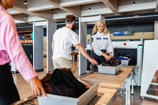 un passager caucasien poussant un plateau pour scanner les bagages aux rayons x - contrôle des bagages photos et images de collection