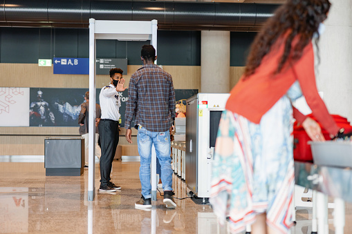 Airport security guard stopping a young adult African male passenger