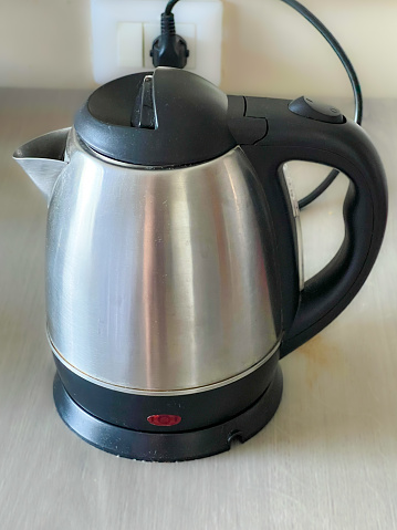Stainless steel kettle on a smooth timber table in a hotel room
