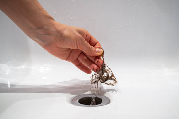 istock Hand pulls hair out of bathroom drain. Cleaning shower polluted sewerage system. 1767858434