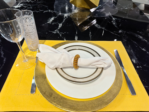 Looking down on a crockery set with napkin ring and napkin crockery on top of a marble dining table
