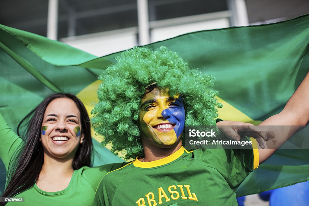 Casal assistindo a um jogo de futebol brasileiro. - Foto de stock de Acenar royalty-free