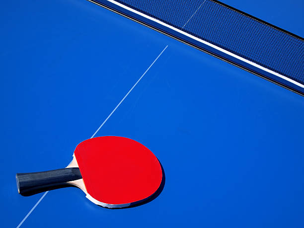 Blue tennis table and red ping pong bat stock photo