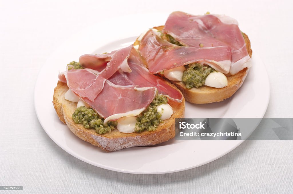 Bruschetta com bocconcini, prosciutto, rúcula e pesto - Foto de stock de Presunto royalty-free