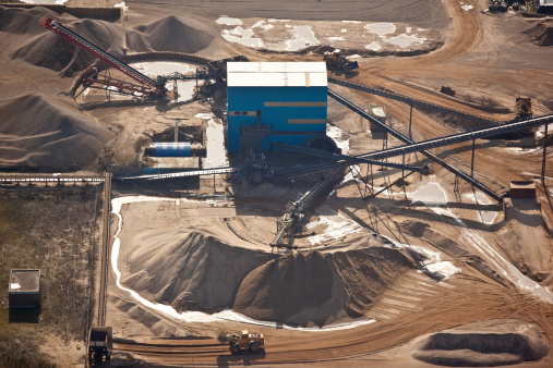 Storage of sand and coal with heavy machinery in a harbor.