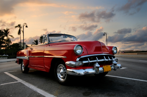 View of red classic vintage american car parked in havana street against sunset sky