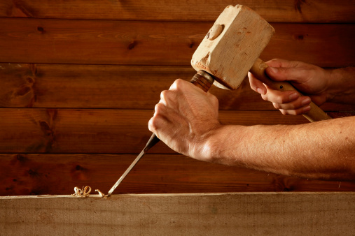 gouge wood chisel carpenter tool hammer in hand working wooden background