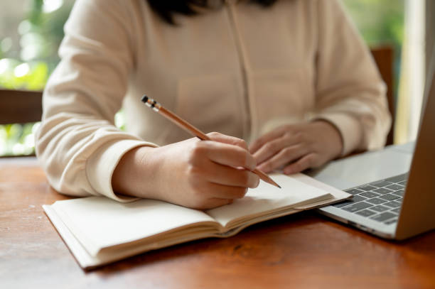 istock An Asian female college student is doing homework, working on her laptop, and taking notes 1767936157