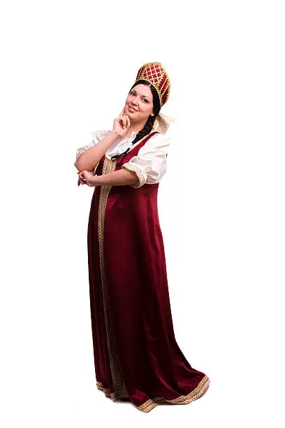 Girl standing in Russian traditional costume. Woman is wearing sarafan and kokoshnik . The girl in red old russian dress. Isolated on white.