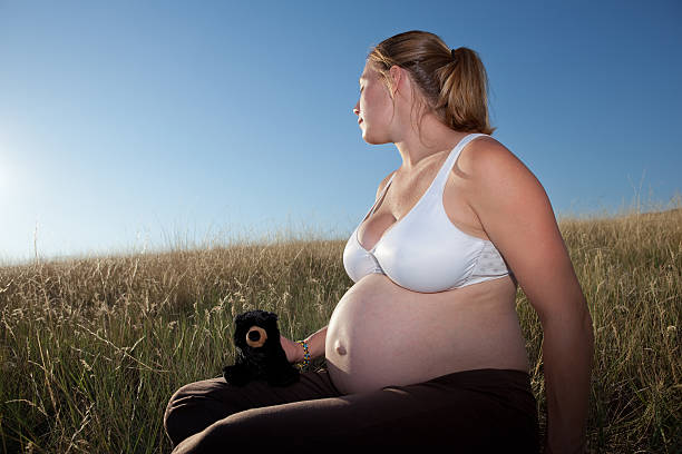 Young Pregnant Woman Sitting in an Open Field stock photo