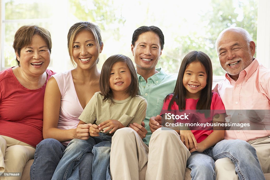 Extended family smiling and relaxing on a sofa at home Extended Family Relaxing On Sofa At Home Together Multi-Generation Family Stock Photo