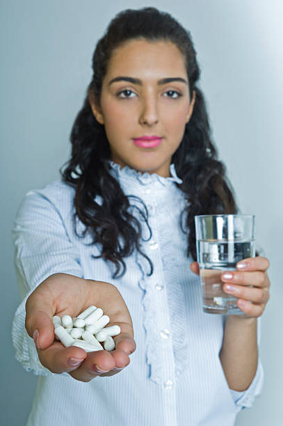 mujer tomando píldoras - wasserglas fotografías e imágenes de stock