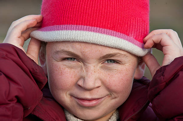 Young girl with freckles adjusting knit cap stock photo