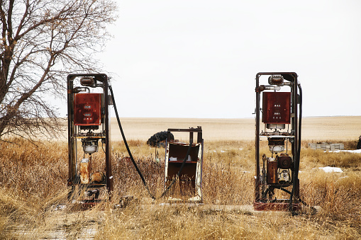 Two old and damaged fuel pumps in a springtime landscape