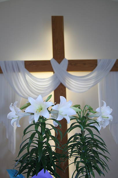 Easter lilies in focus with glowing cross background