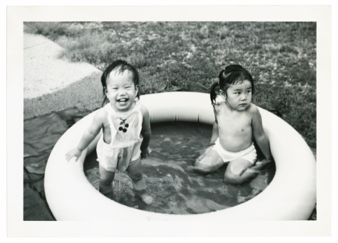 asian children playing in a pool, scanned photograph, 1950's, DOF, focus on child on right, some dust and scratches left in to show age